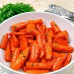 Air fried carrots in a white bowl with some parsley in the background.