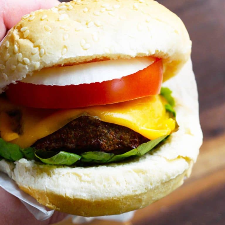 Air fryer turkey burger in a white sesame bun with lettuce, tomato, onion, and cheese.
