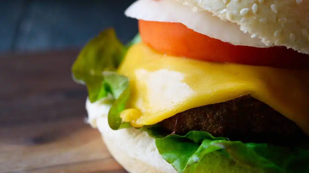 A close up picture of air fryer turkey burger in between buns, lettuce, tomato, onion, and cheese.