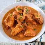 Butter chicken in a round white dish.