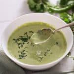 Cilantro mint chutney in a white bowl with a spoon.