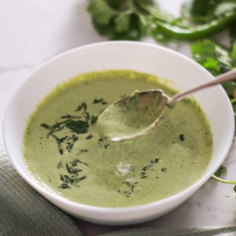 Cilantro mint chutney in a white bowl with a spoon.