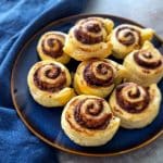 Puff pastry nutella rolls on a blue plate with a blue napkin in the background.