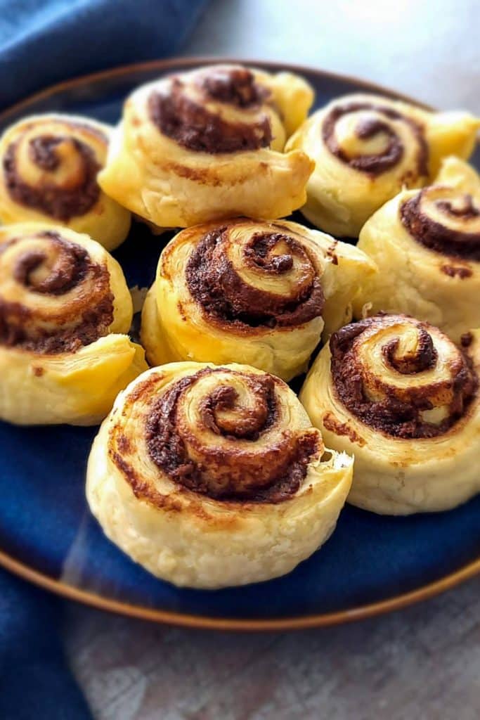 Nutella rolls with puff pastries on a blue plate.