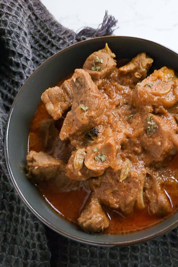 Lamb curry in a black bowl with black tea towel next to it.
