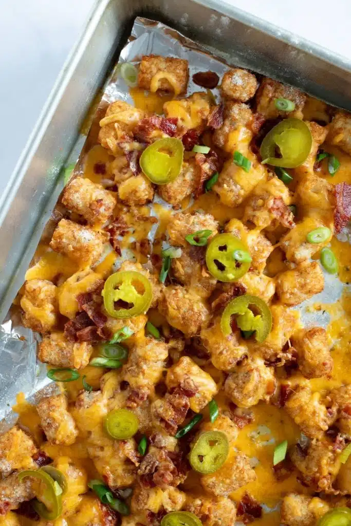 Loaded tater tots on a baking tray.