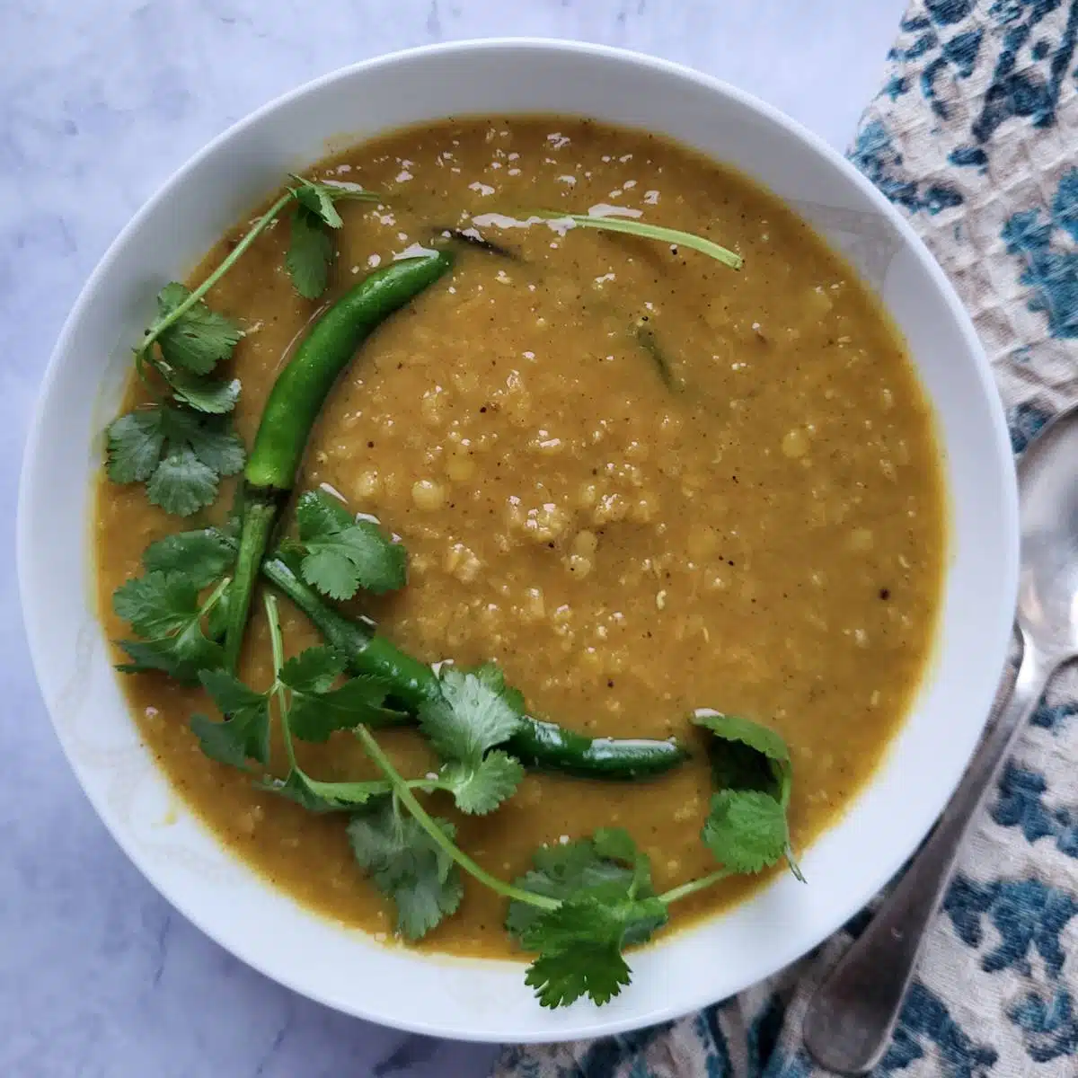A bowl of Masoor Dal with cilantro and green chilies garnish.