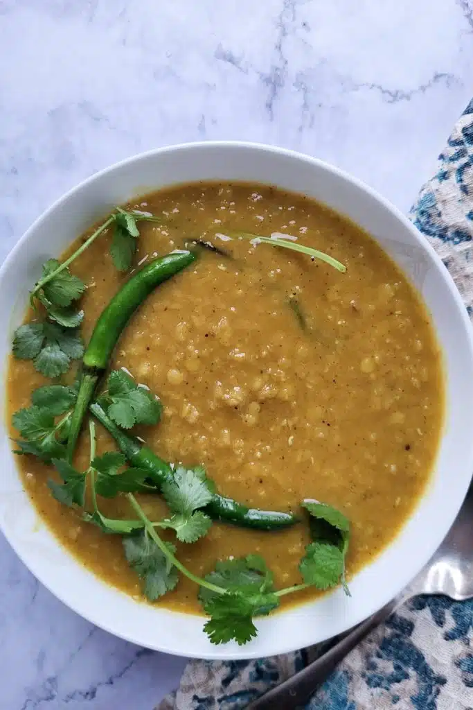 Red lentil curry garnished with cilantro and green chilies.
