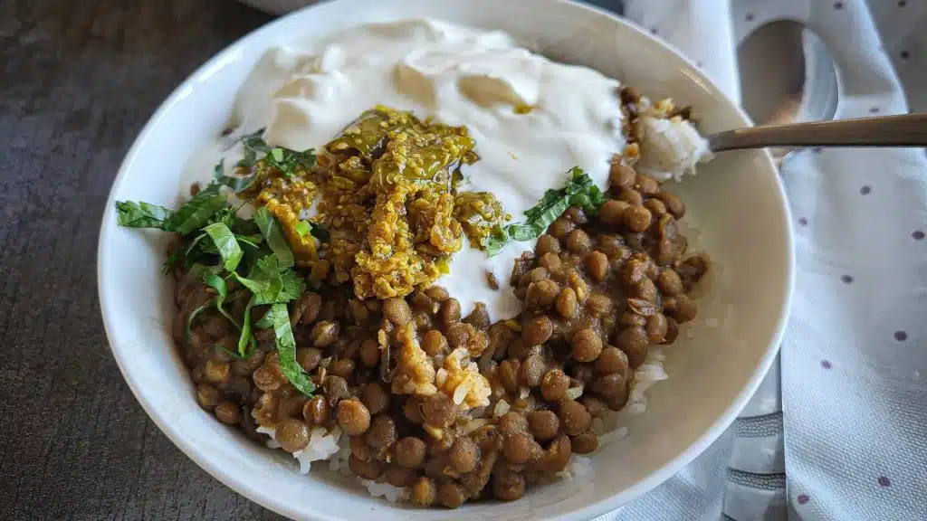 A bowl of whole masoor dal with rice, yogurt and achar.