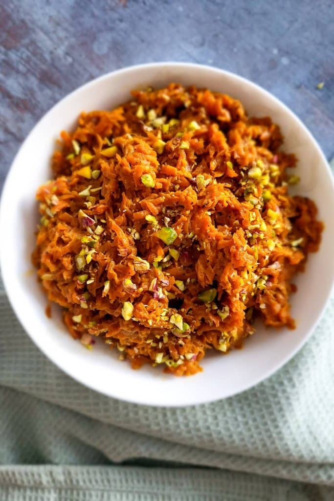 Carrot halwa in a round dish with mint napkin in the background.