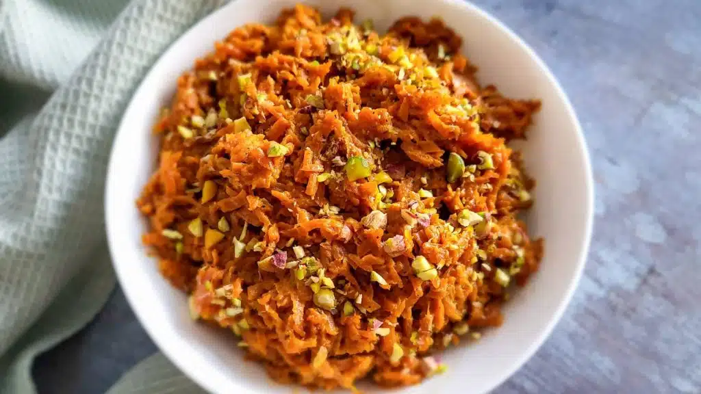 Gajar ka Halwa in a white bowl with mint napkin in the background.