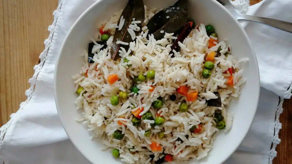 A deep plate of vegetable pilau rice with white napkin in the background.