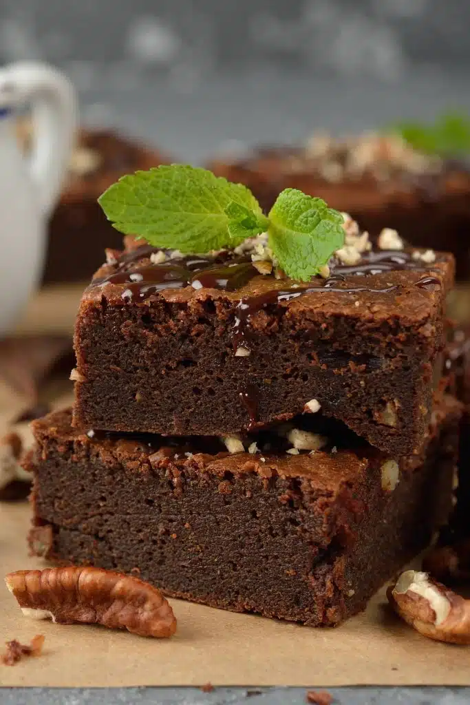 Two pieces of stacked chocolate brownies with mint leaves on the the top.