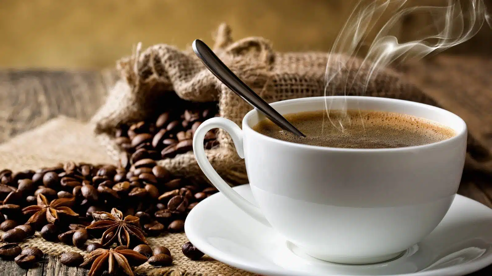 A cup of black coffee with coffee beans around it.