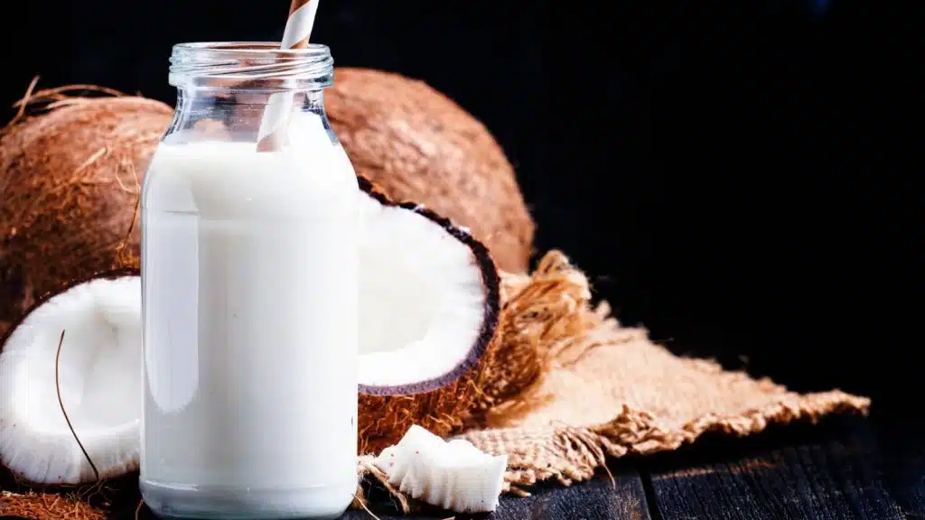 Coconut milk in a bottle with coconuts.