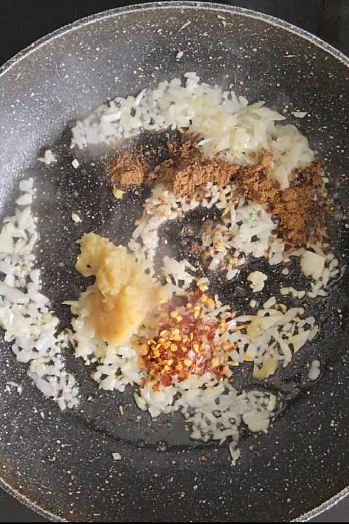 Chopped onions and spices on a skillet.