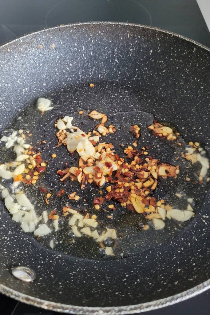 Frying red pepper flakes and garlic in a pan.