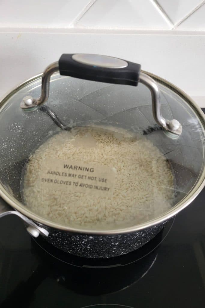 Raw glutinous rice in a saucepan with the lid on.