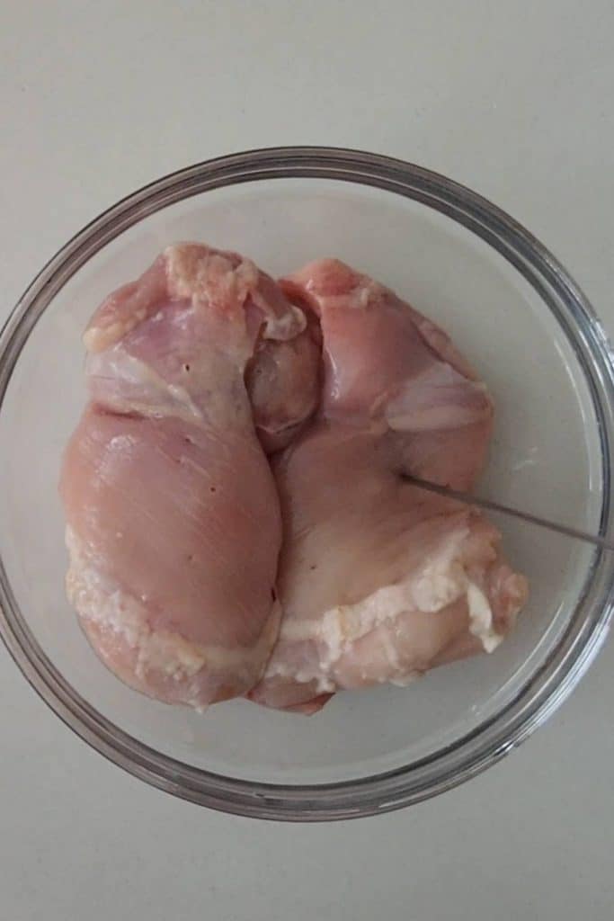 Raw chicken thighs in a mixing bowl.