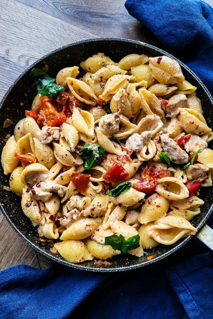 Pasta and chicken with sundried tomatoes and basil leaves.