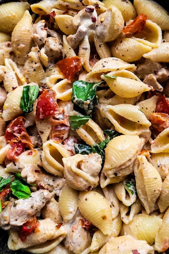 Pasta shells in creamy sun dried tomato sauce with chicken and fresh basil leaves.