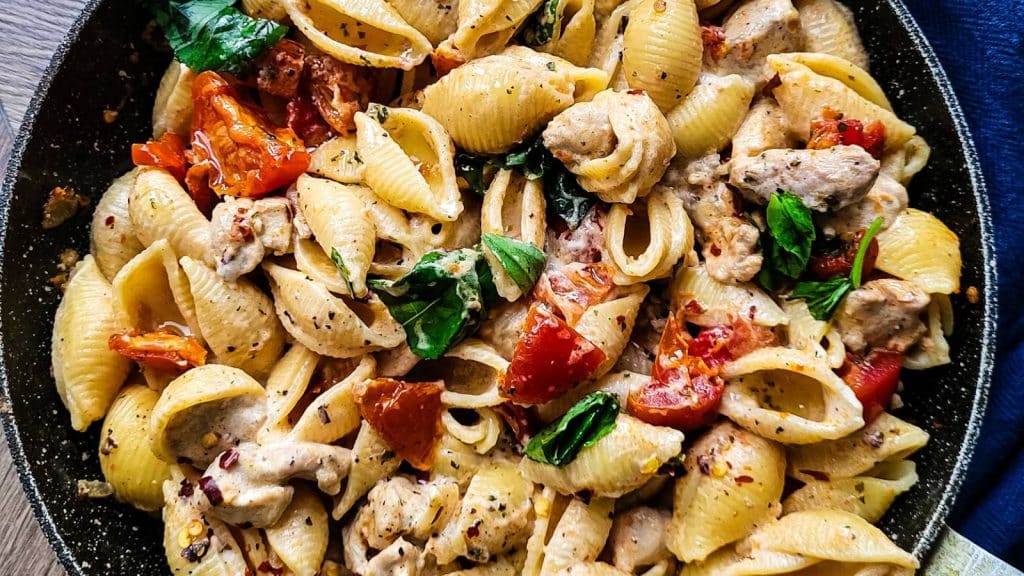 Sun dried tomato pasta with chicken in a frying pan.