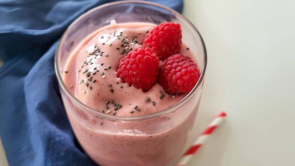 Raspberry smoothie with blue napkin on the side.