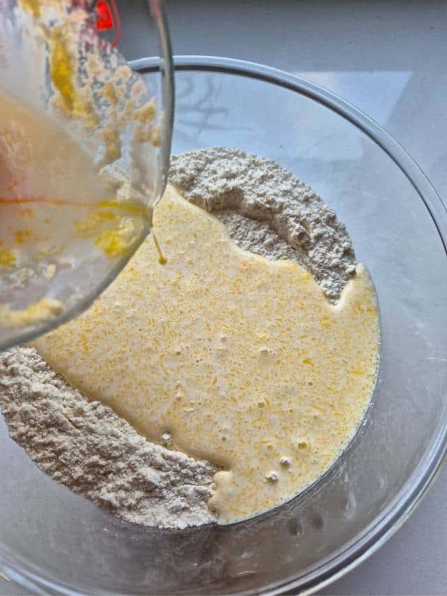 A mix of melted butter and cream pouring into flour mixture.