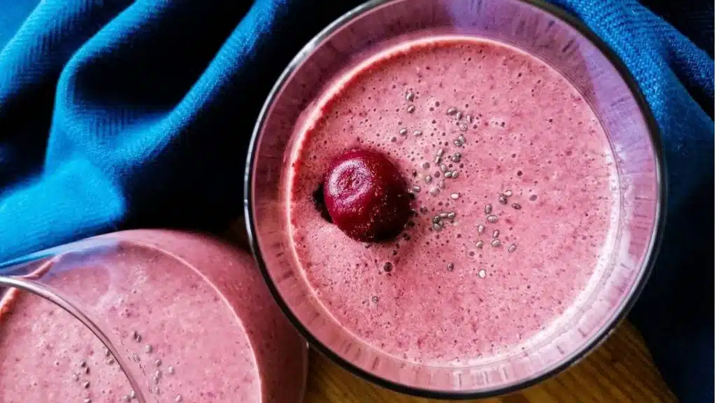 Glasses of cherry smoothie with blue napkin in the background.