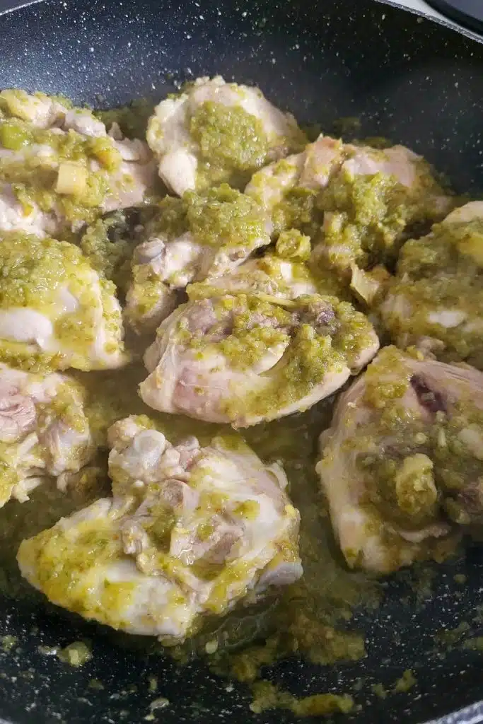 Chicken and green chili spice paste in frying pan.