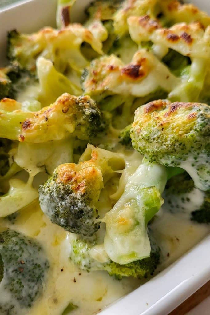 Cheesy broccoli casserole in a white dish.