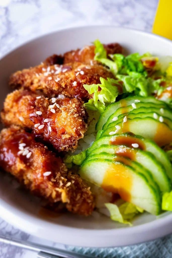 Close-up of Chicken Katsu with green veggies in a bowl.