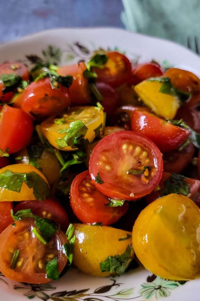 Close-up of sliced ripe tomatoes glistening with olive oil and scattered with fresh parsley.