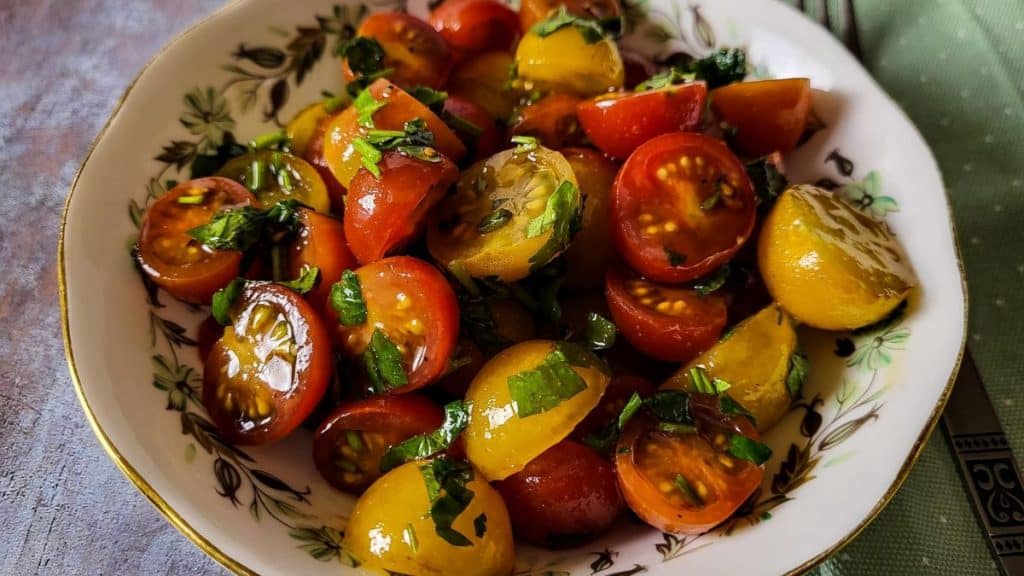 Italian tomato salad in a bowl with green mint napkin in the background.