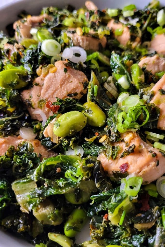 Close-up green kale salad with spiced salmon.