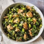 Salmon kale salad with edamame beans and spring onions in a white pasta bowl.