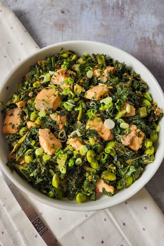 A bowl of salmon salad with green kale.