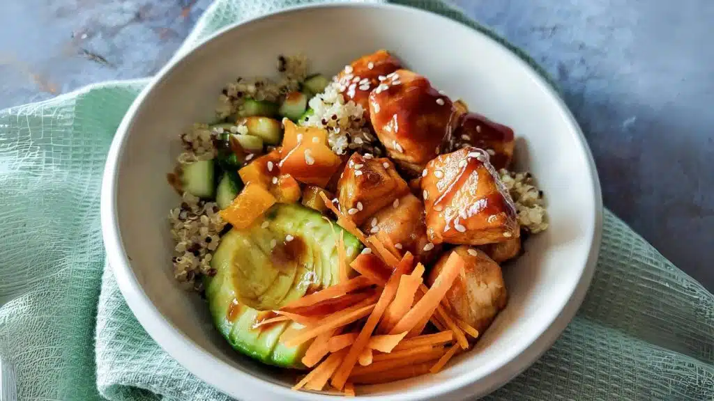 Salmon quinoa bowl with avocado, carrots, and cucumbers.