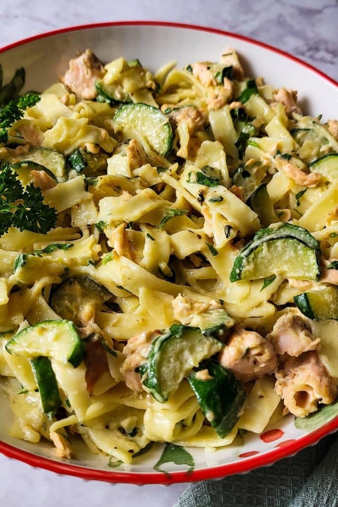 Close-up of flaked salmon and zucchini tossed through pasta in a light cream sauce.