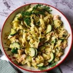 Salmon and zucchini pasta in a bowl with creamy sauce and fresh herbs