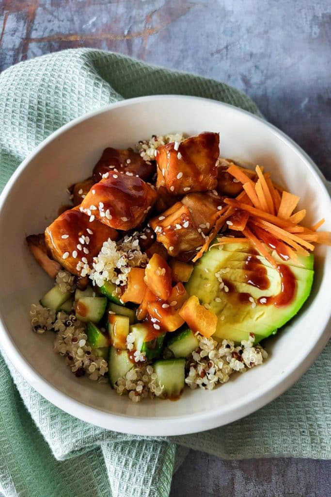 A close-up of Salmon Quinoa Bowl with cucumber, carrot, and avocado.