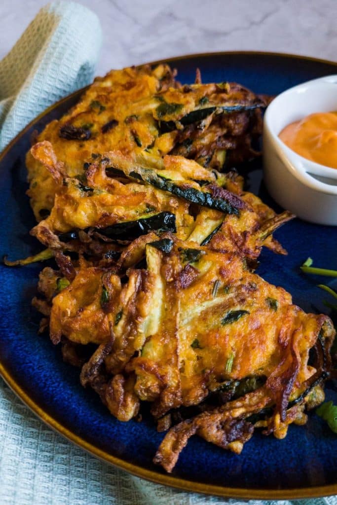 A few pieces of sweet potato zucchini fritters on a blue plate.