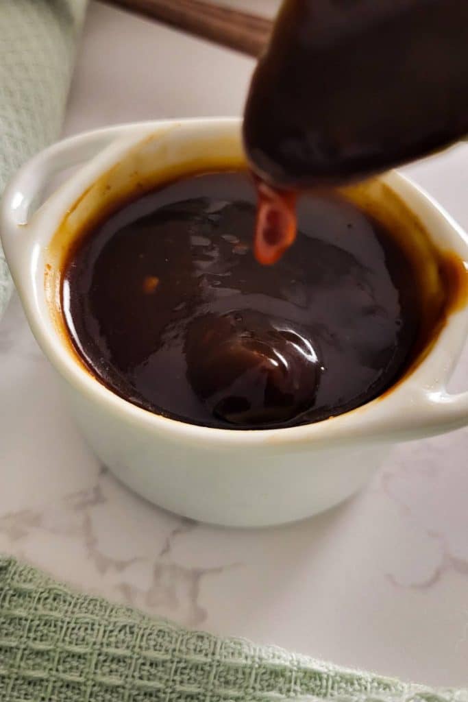 Homemade tonkatsu sauce in a white bowl with a spoon over it.