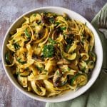 Zucchini mushroom pasta with mint green napkin in the background.