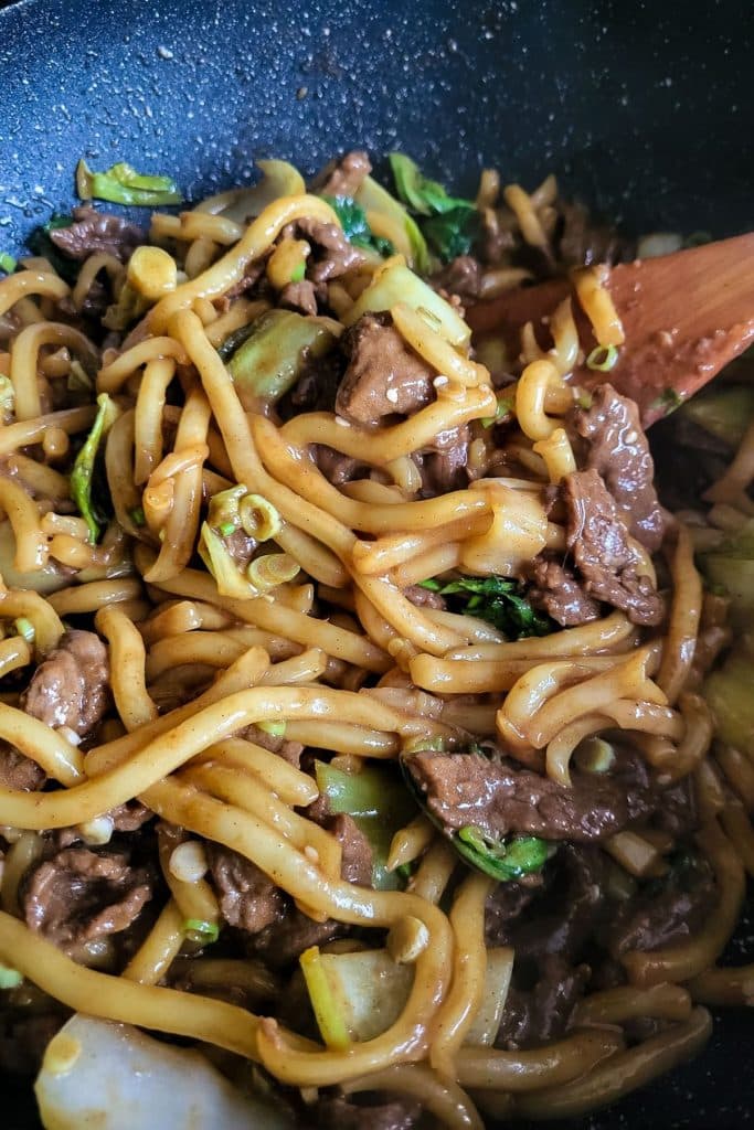 Stir fried beef udon noodles with pak choi and sliced scallions.